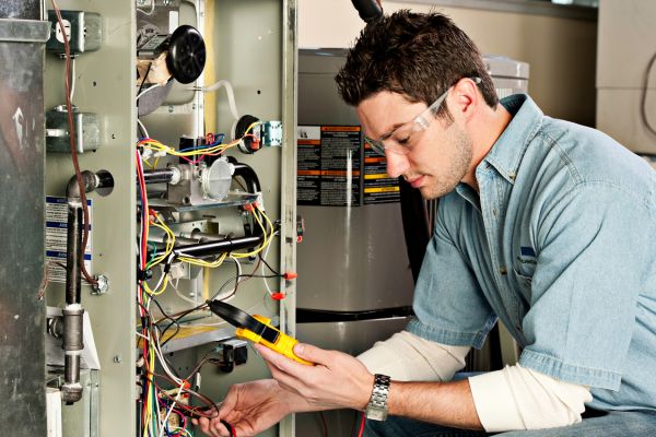 Trusted Rheem furnace service & replacement technician in King and Snohomish Counties using a multimeter to test internal components of a home heating system.